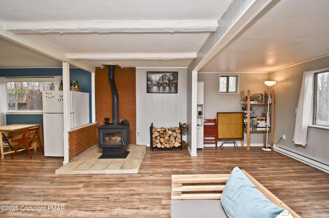 living room featuring beam ceiling, wood finished floors, and a wood stove