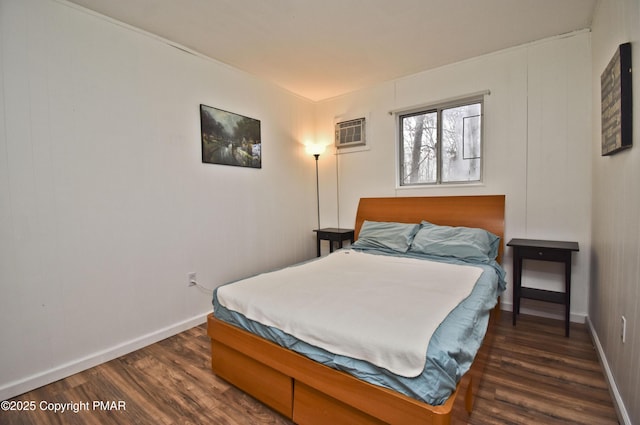 bedroom featuring a wall unit AC, baseboards, and dark wood-style flooring