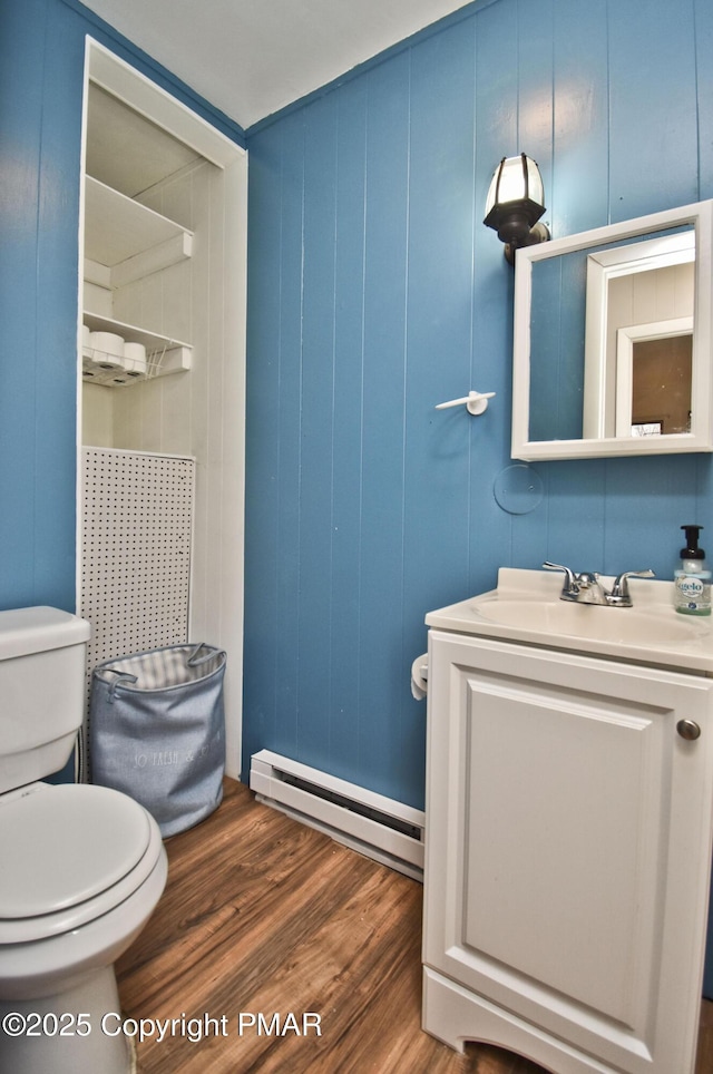 bathroom featuring toilet, vanity, baseboard heating, and wood finished floors