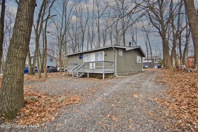 view of front of home with crawl space and gravel driveway