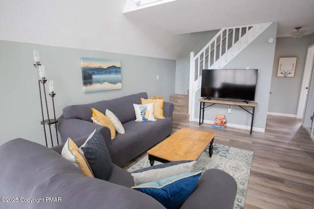 living area with stairs, vaulted ceiling, wood finished floors, and baseboards