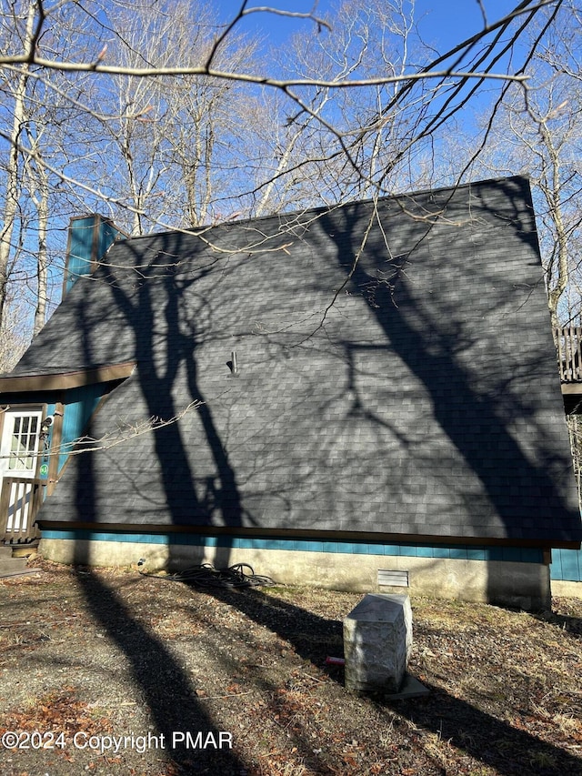 view of side of home with a shingled roof