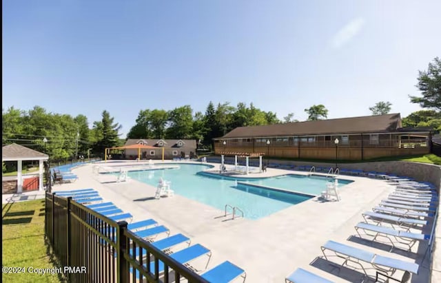 community pool with a patio area and fence