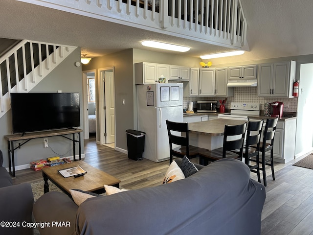 living room with stairway, light wood-style flooring, and baseboards