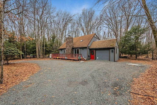 view of front of home with driveway, a garage, a shingled roof, a chimney, and a deck