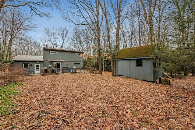 back of house featuring a shed, a deck, and an outbuilding