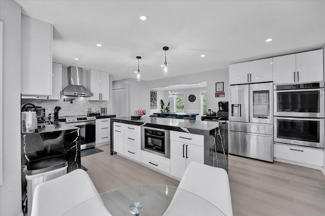 3336 Buck Run, Tobyhanna, PA 18466 - kitchen with stainless steel appliances, wall chimney range hood, light wood-type flooring, dark countertops, and decorative backsplash