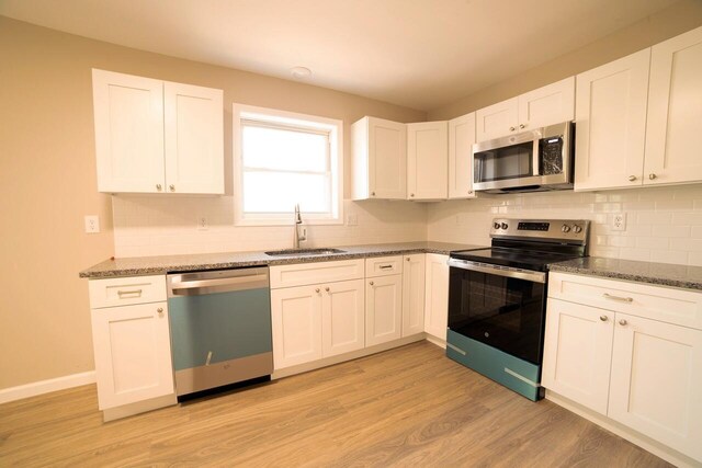 663 Sullivan Trl, Long Pond, PA 18334 - kitchen with stainless steel appliances, a sink, dark stone counters, and light wood-style flooring