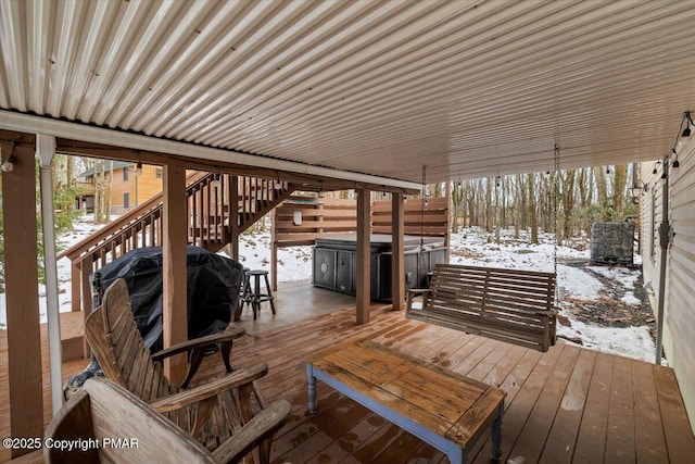 snow covered deck with area for grilling and a hot tub