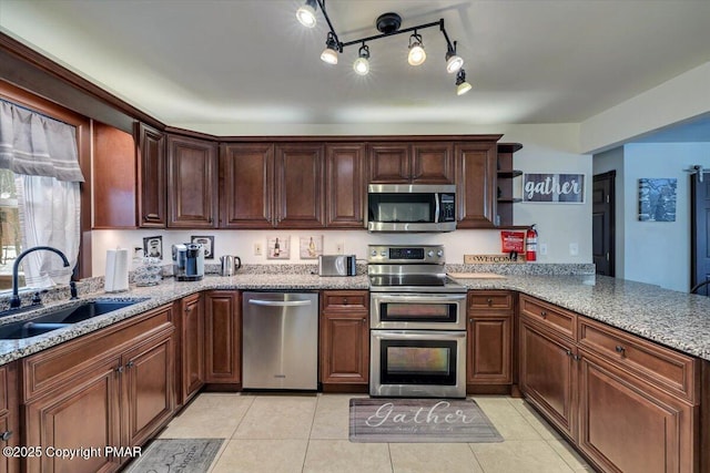 kitchen with sink, light stone counters, light tile patterned floors, kitchen peninsula, and stainless steel appliances