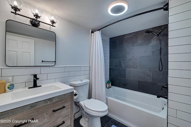 bathroom with wainscoting, toilet, shower / tub combo with curtain, vanity, and tile walls