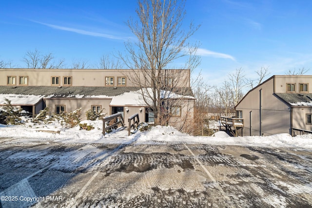 snow covered rear of property with stucco siding