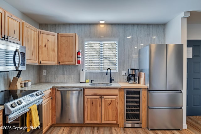 kitchen featuring light wood-style flooring, wine cooler, stainless steel appliances, light countertops, and a sink