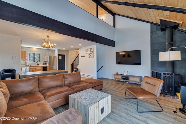 living area with wooden ceiling, a notable chandelier, stairs, light wood finished floors, and a wood stove