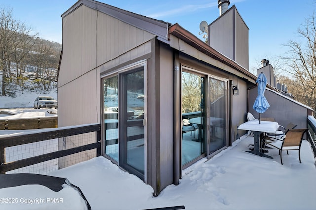 view of snow covered exterior with a chimney