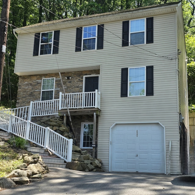 2545 S Albert St, Allentown, PA 18103 - view of front facade with stone siding, a garage, covered porch, and view of scattered trees