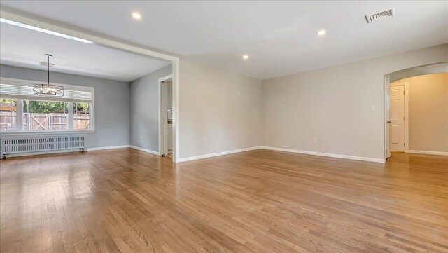 2705 W Gordon St, Allentown, PA 18104 - spare room featuring radiator, light wood-style floors, arched walkways, a chandelier, and recessed lighting