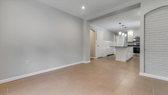 2705 W Gordon St, Allentown, PA 18104 - kitchen with stainless steel appliances, white cabinetry, a kitchen island, dark countertops, and arched walkways