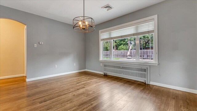 2705 W Gordon St, Allentown, PA 18104 - spare room featuring radiator, hardwood / wood-style floors, arched walkways, and a chandelier