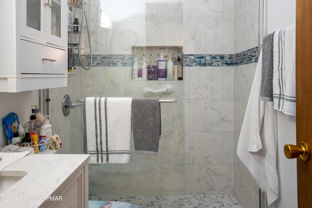 full bathroom with a tile shower and vanity