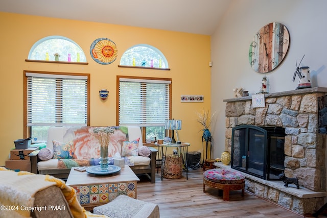 living room featuring vaulted ceiling, a fireplace, and wood finished floors