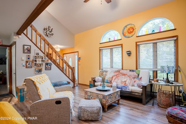 living area featuring stairs, ceiling fan, high vaulted ceiling, and wood finished floors