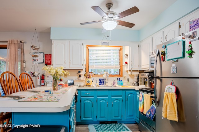 kitchen featuring white cabinets, electric stove, freestanding refrigerator, a peninsula, and light countertops