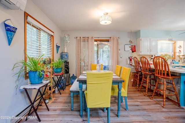 dining area with light wood finished floors and a wall mounted air conditioner