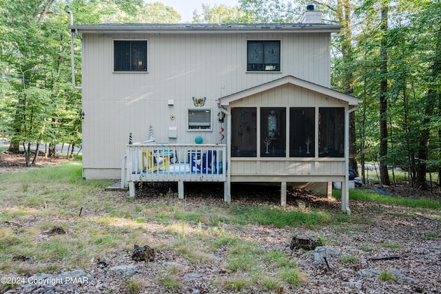 rear view of property with a chimney and a sunroom