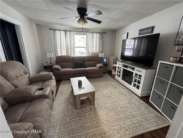 living room featuring wood-type flooring, a drop ceiling, and ceiling fan