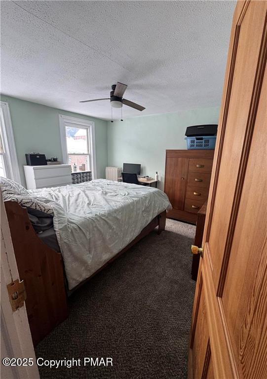 carpeted bedroom featuring ceiling fan, radiator, and a textured ceiling