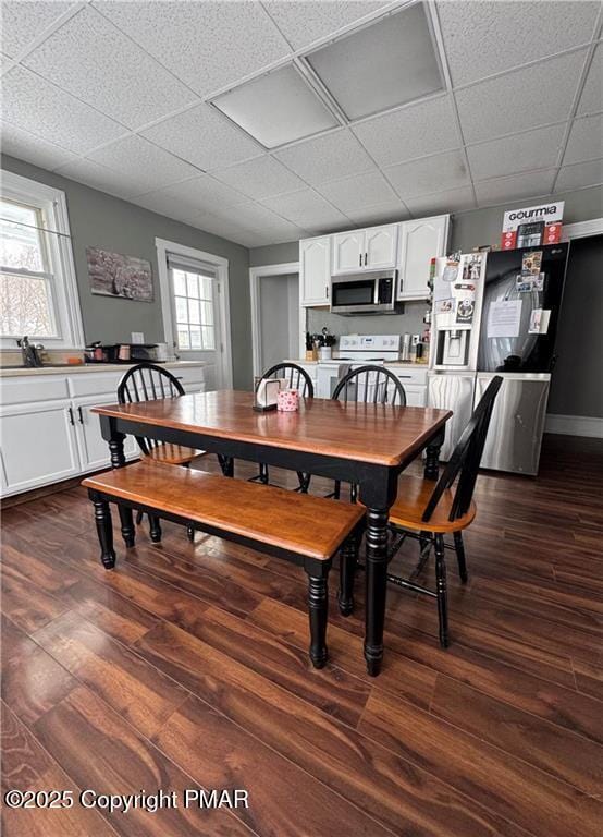 dining area with dark hardwood / wood-style floors and a drop ceiling