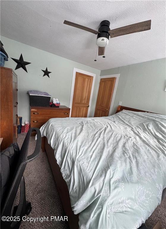 carpeted bedroom featuring ceiling fan and a textured ceiling