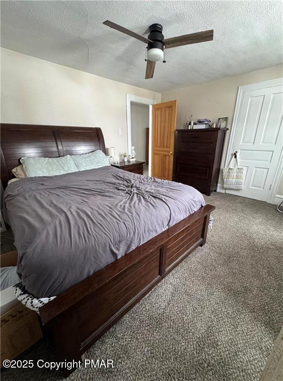 carpeted bedroom with ceiling fan and a textured ceiling