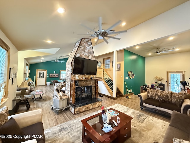 living area featuring plenty of natural light, lofted ceiling, a fireplace, and stairs