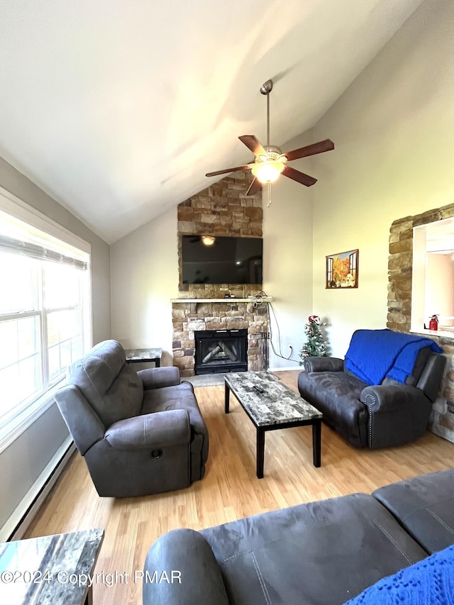 living room with a baseboard heating unit, lofted ceiling, a stone fireplace, wood finished floors, and a ceiling fan