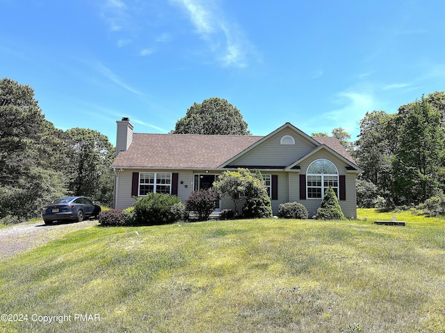 ranch-style house featuring a chimney, a front yard, and a shingled roof