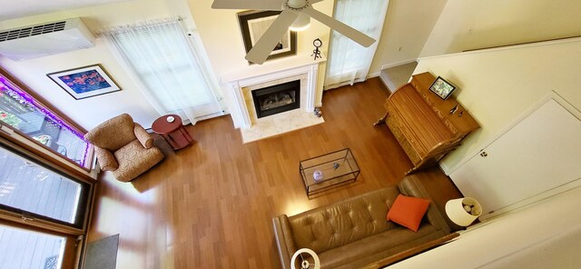 210 Dover Dr, Bushkill, PA 18324 - living room featuring a ceiling fan, wood finished floors, a premium fireplace, an AC wall unit, and plenty of natural light