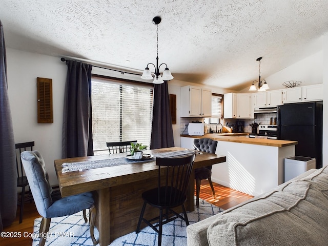 dining area featuring lofted ceiling, hardwood / wood-style flooring, a wealth of natural light, and a chandelier