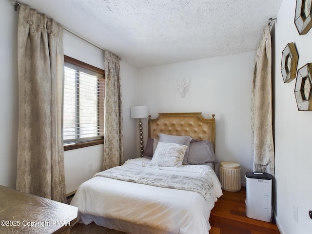 bedroom with a textured ceiling and dark hardwood / wood-style flooring