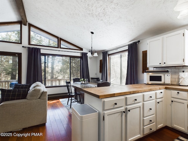 kitchen with wooden counters, white cabinetry, hanging light fixtures, vaulted ceiling with beams, and dark hardwood / wood-style flooring