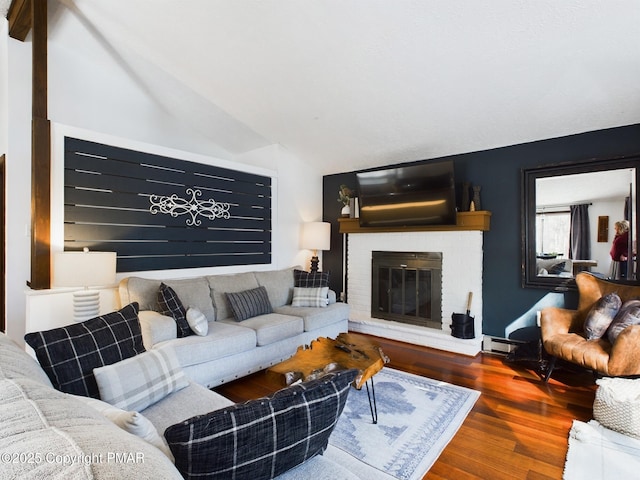 living room with a fireplace, vaulted ceiling, and hardwood / wood-style floors