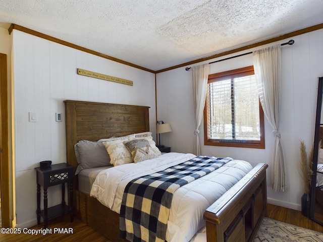 bedroom featuring wood-type flooring, ornamental molding, and a textured ceiling