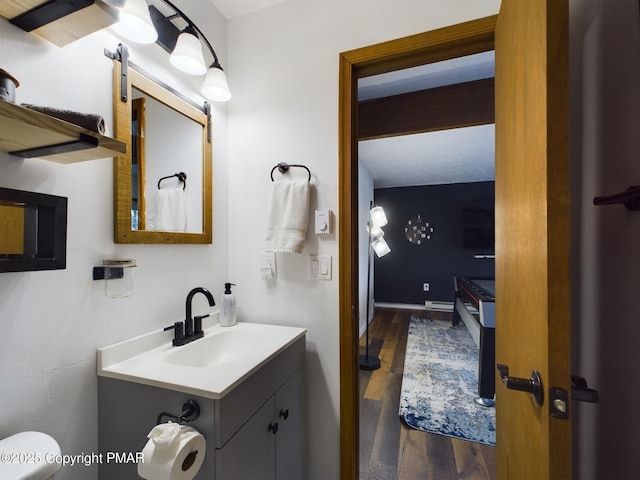 bathroom with vanity, hardwood / wood-style flooring, beamed ceiling, and toilet