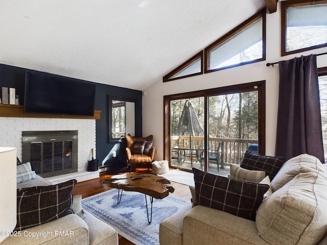 living room with wood-type flooring, lofted ceiling, a textured ceiling, and a brick fireplace