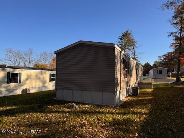 view of property exterior featuring central AC and a lawn