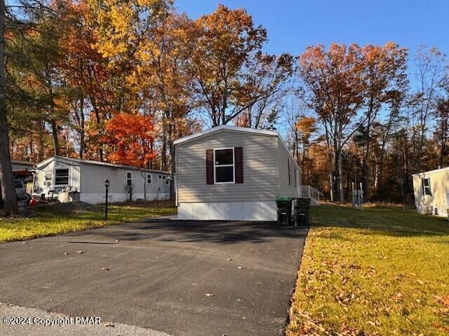 view of property exterior with aphalt driveway and a lawn