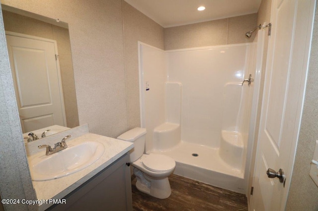 bathroom with toilet, a shower, wood finished floors, and vanity