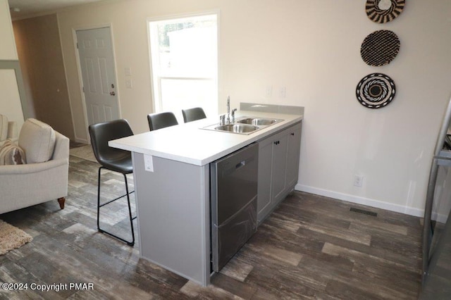 kitchen with visible vents, dark wood finished floors, dishwasher, a kitchen breakfast bar, and a sink