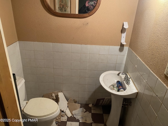 bathroom featuring toilet, sink, and tile walls